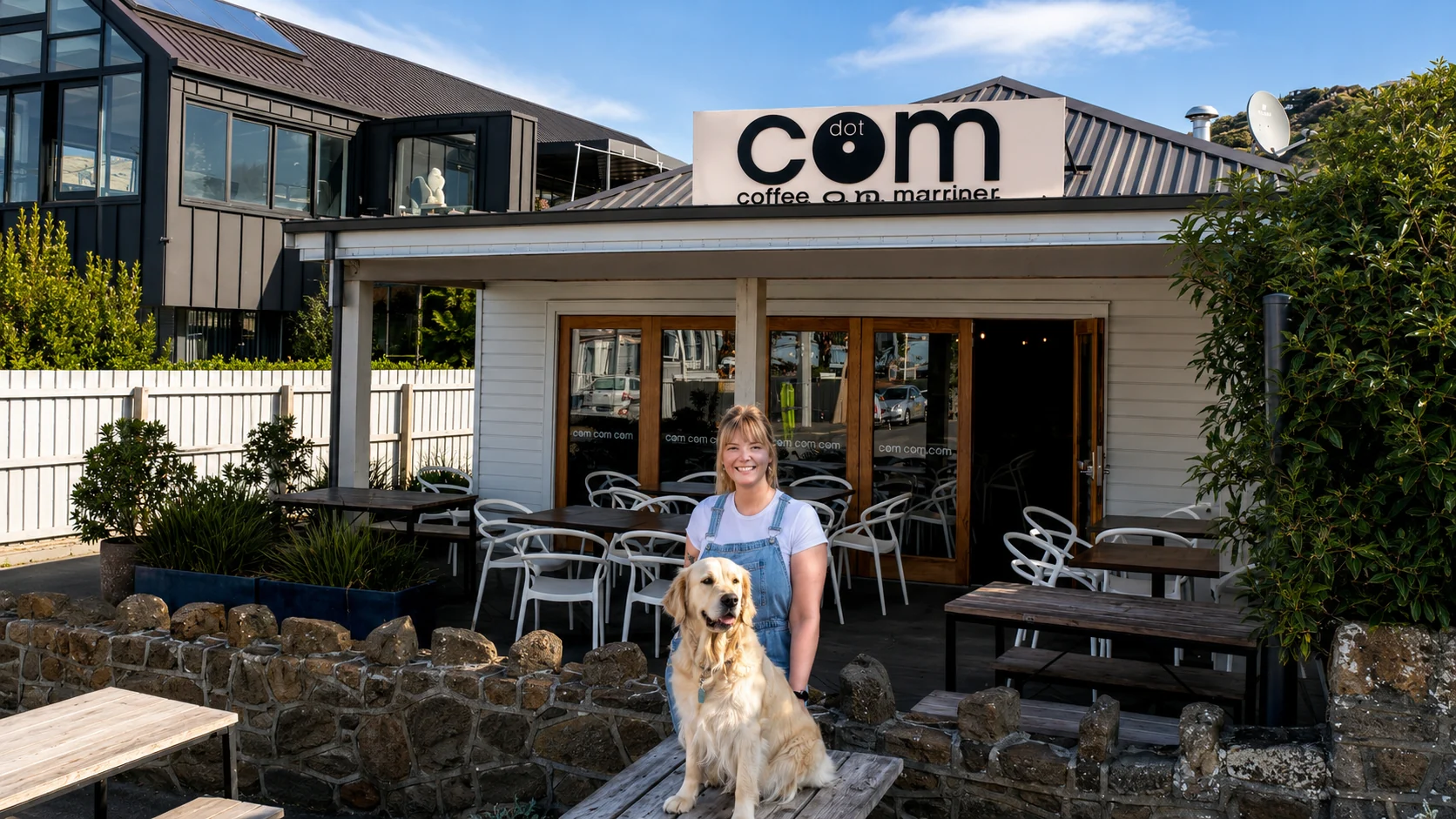 A staff member with a golden retriever outside Dot Com Cafe